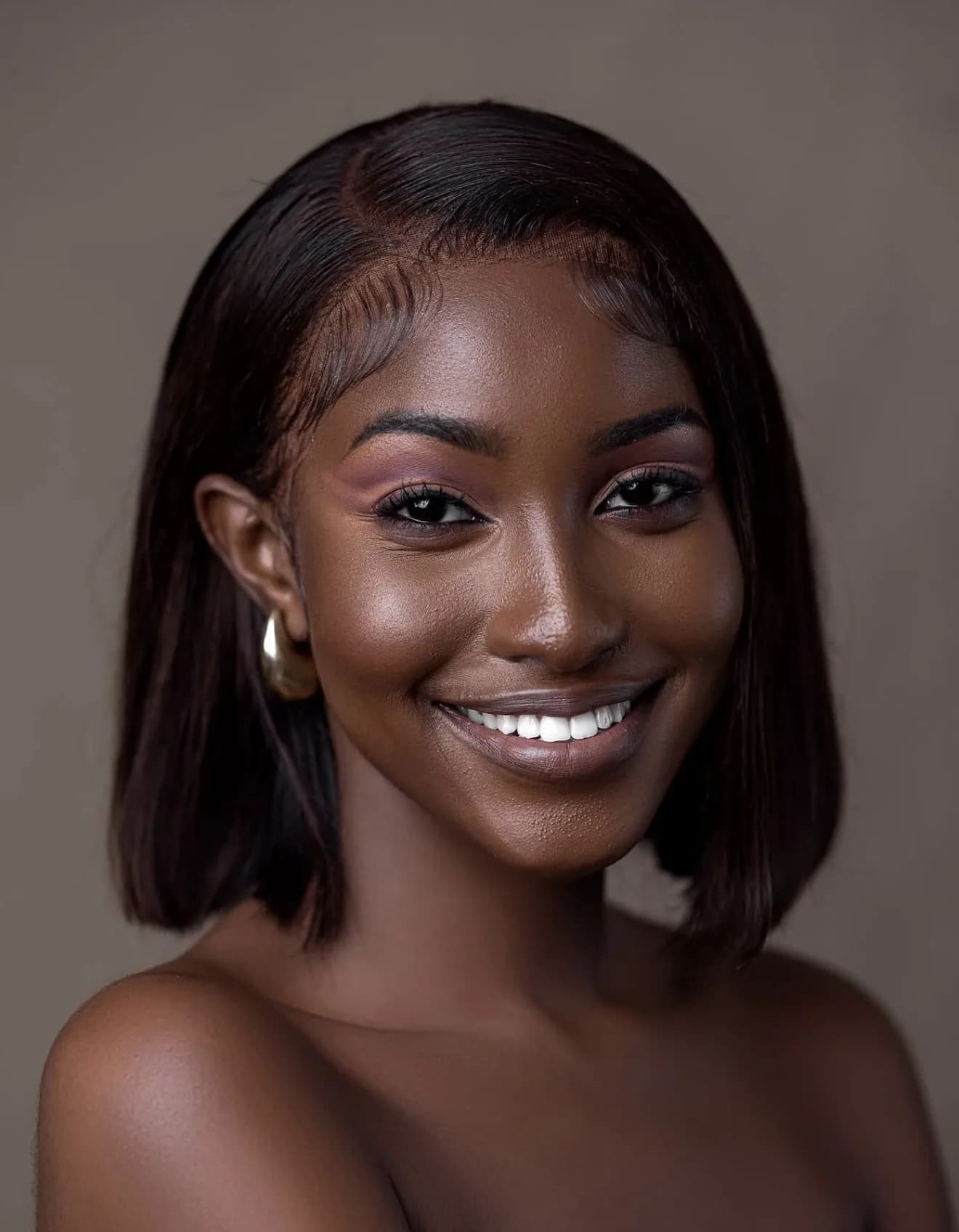 A woman smiling to camera in gold hoop earrings