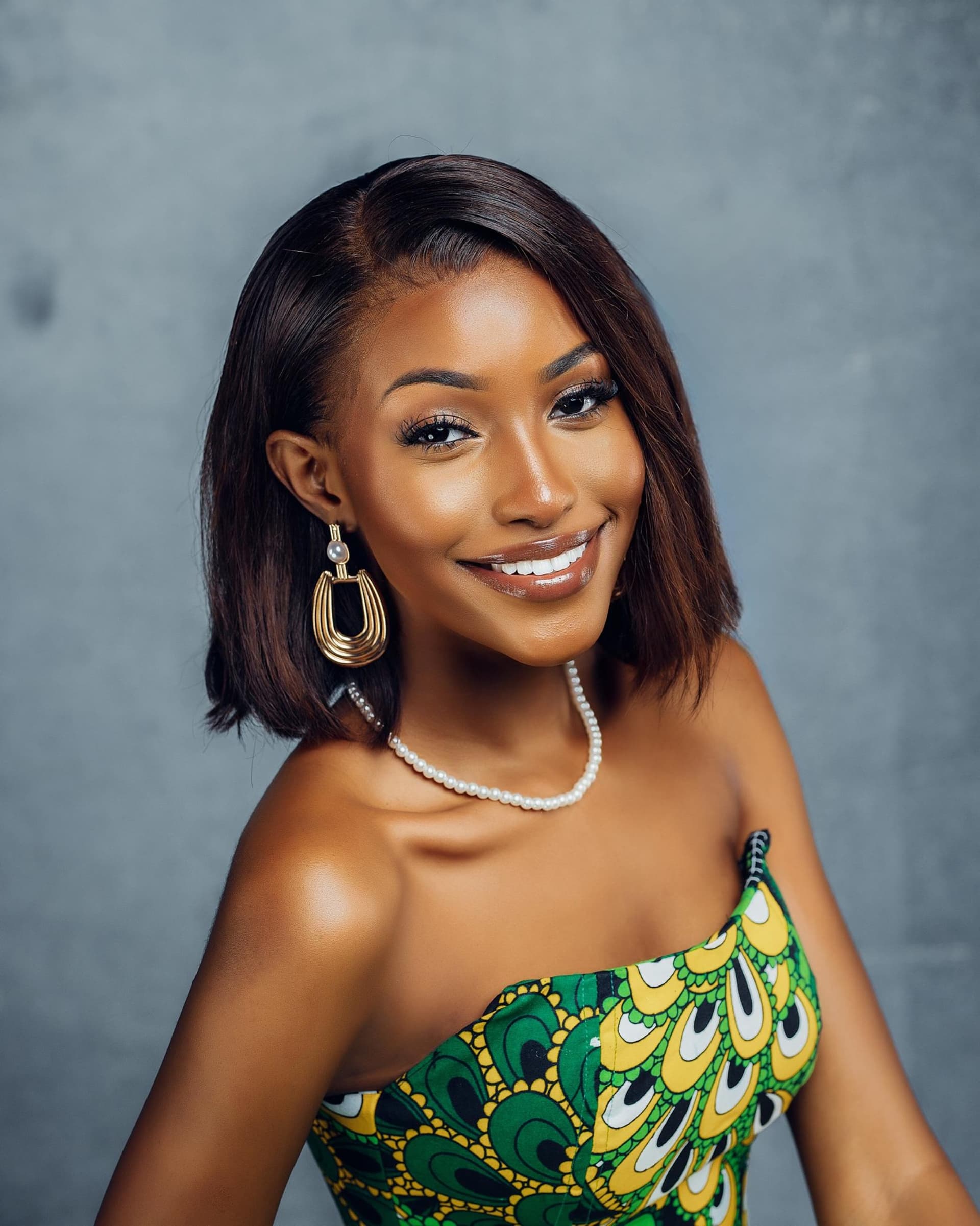 A smiling Miss Tanzania contestant in a green and gold dress