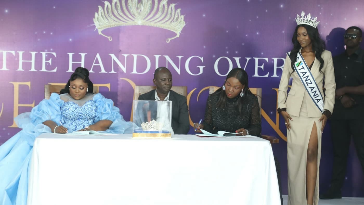 The Miss Tanzania handover ceremony in Dar es Salaam, with the outgoing and incoming organisers signing at a table beside the reigning titleholder