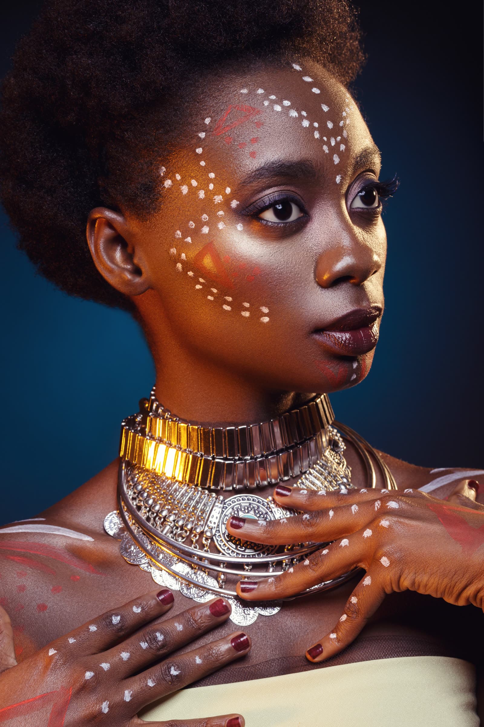 A woman in white face paint and layered neck rings
