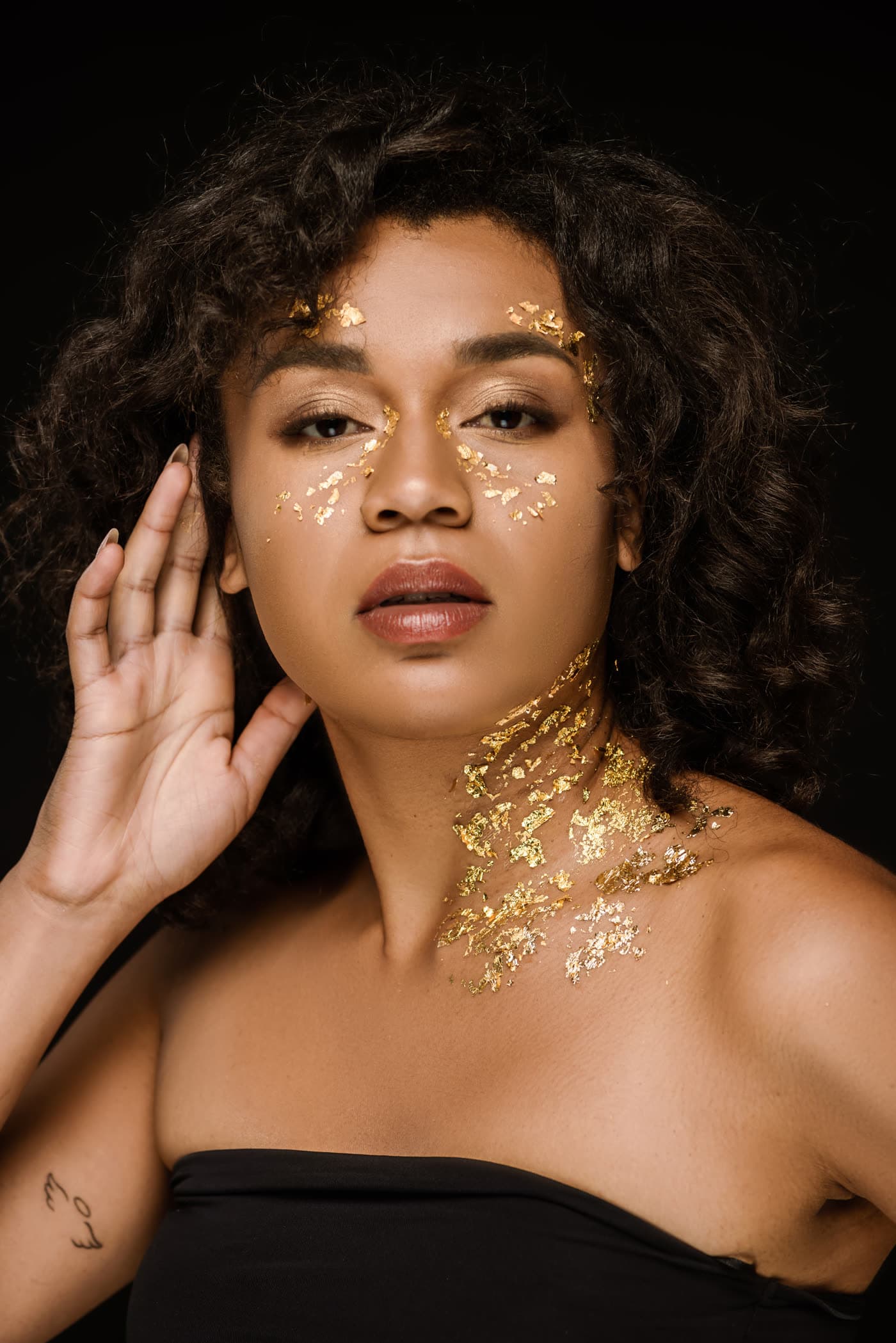 A woman with gold flakes across her face and neck