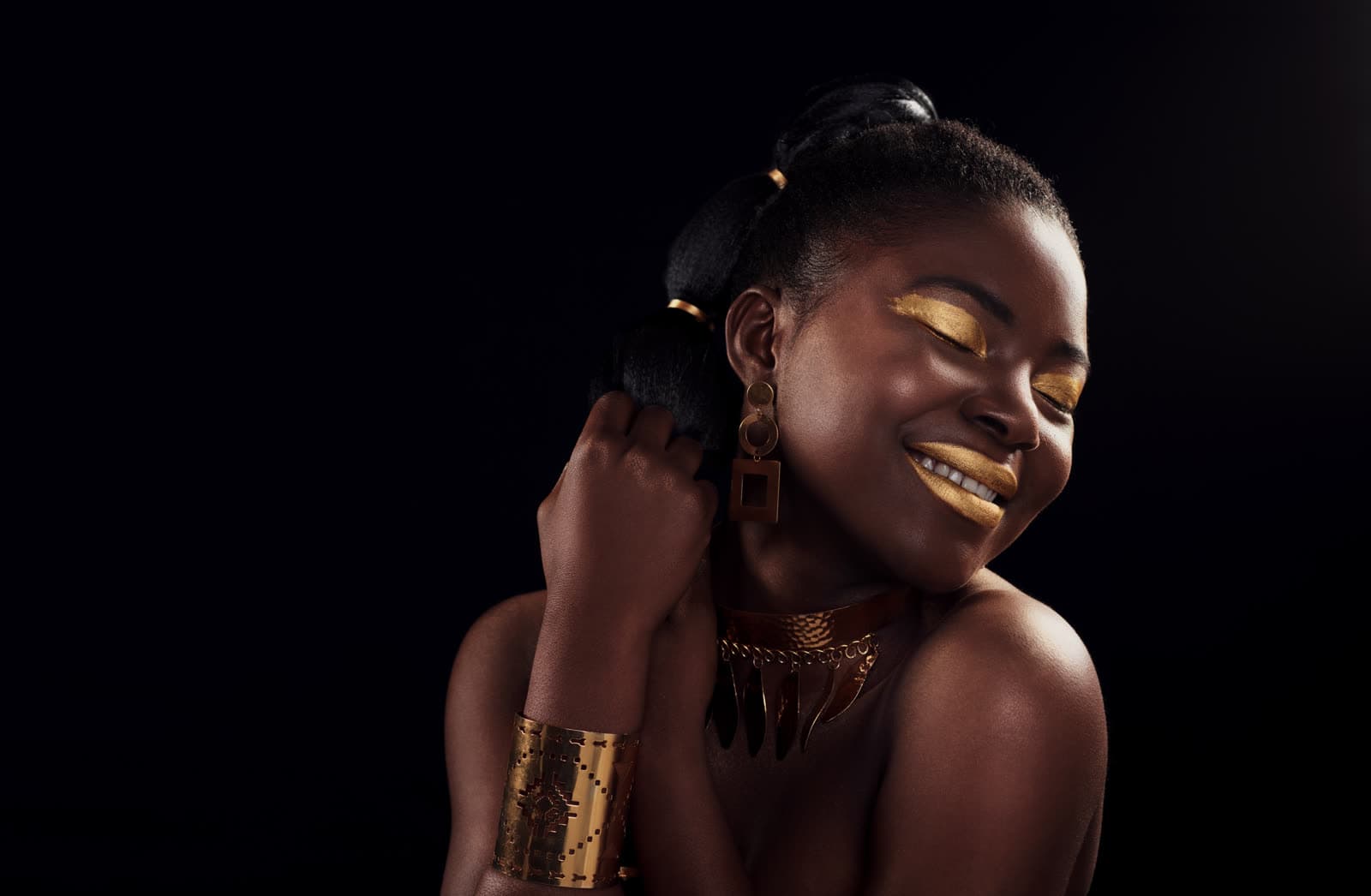A woman in gold makeup and jewellery, smiling