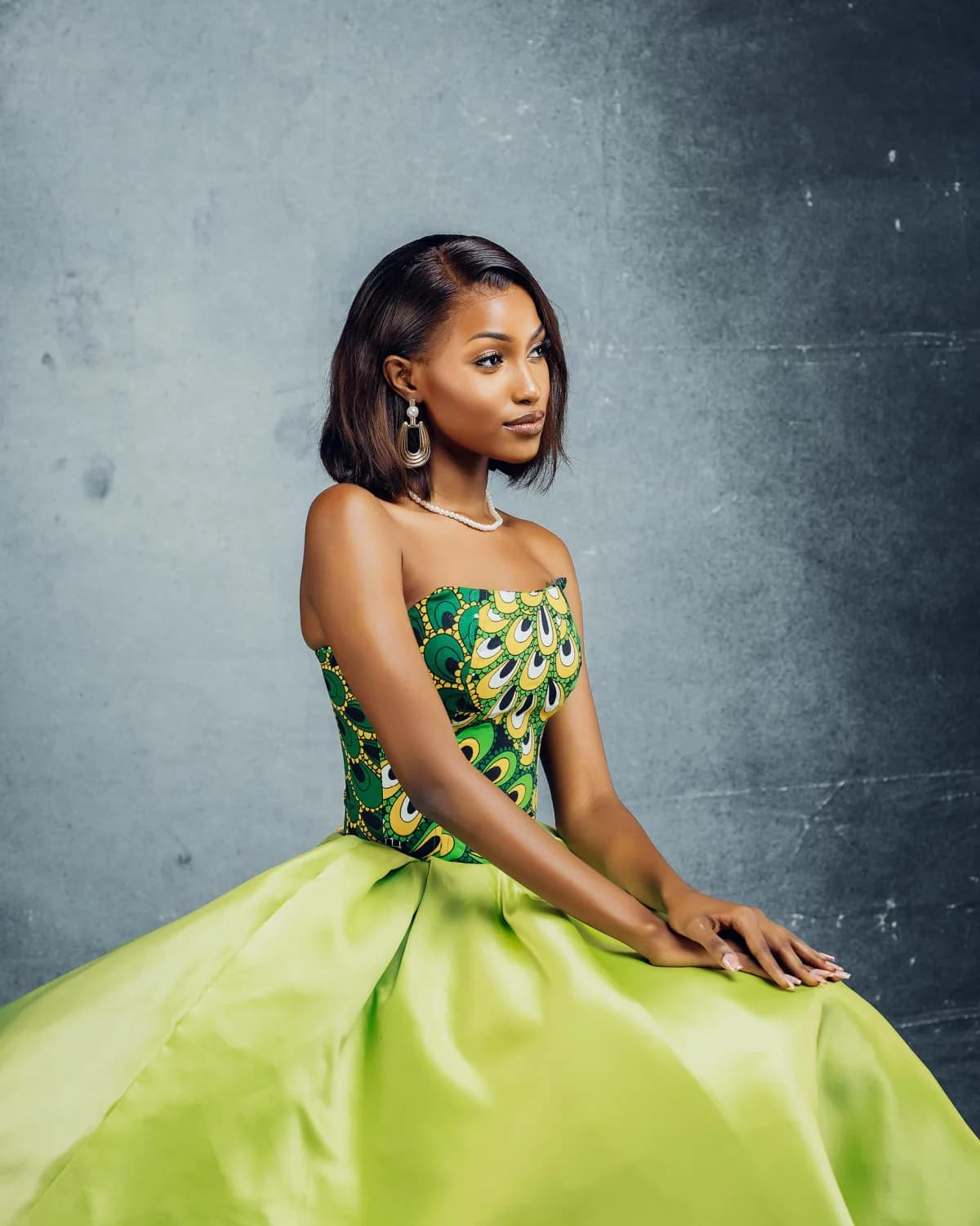 Studio portrait of a woman in a green kitenge and satin gown